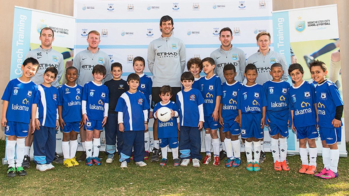 Black Aces Academy — kids in Lakama-sponsored kits with Manchester City School of Football coaches